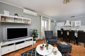 Relax in this stylish living space with a flat-screen TV, dining area for four, and a cozy armchair.