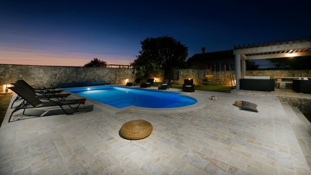 Un espace extérieur avec une piscine, des chaises longues et une terrasse en pierre.
