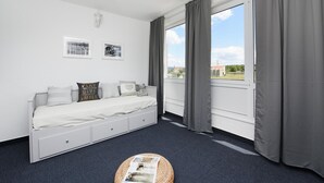 Une chambre d’hôtel moderne, équipée d’un lit, d’une petite table et offrant une vue sur l’extérieur.