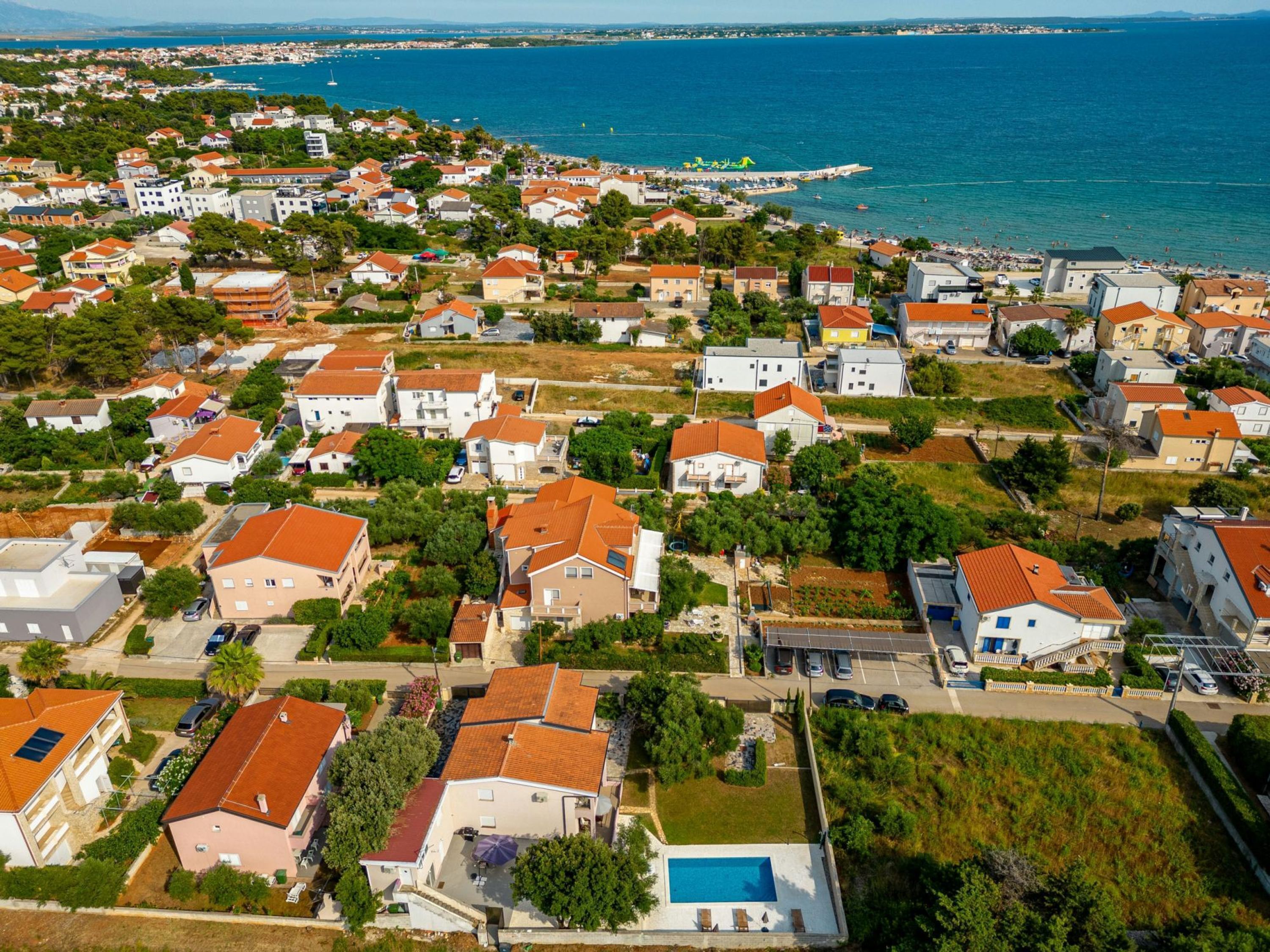 A residential area with houses, a swimming pool, and a view of the sea.