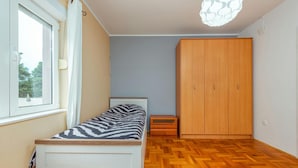Une chambre à coucher comprenant un lit, une armoire, une fenêtre et un parquet à motifs en chevrons.