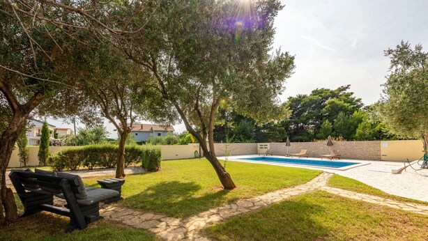 Un jardin avec une piscine, un chemin de pierres et un banc.