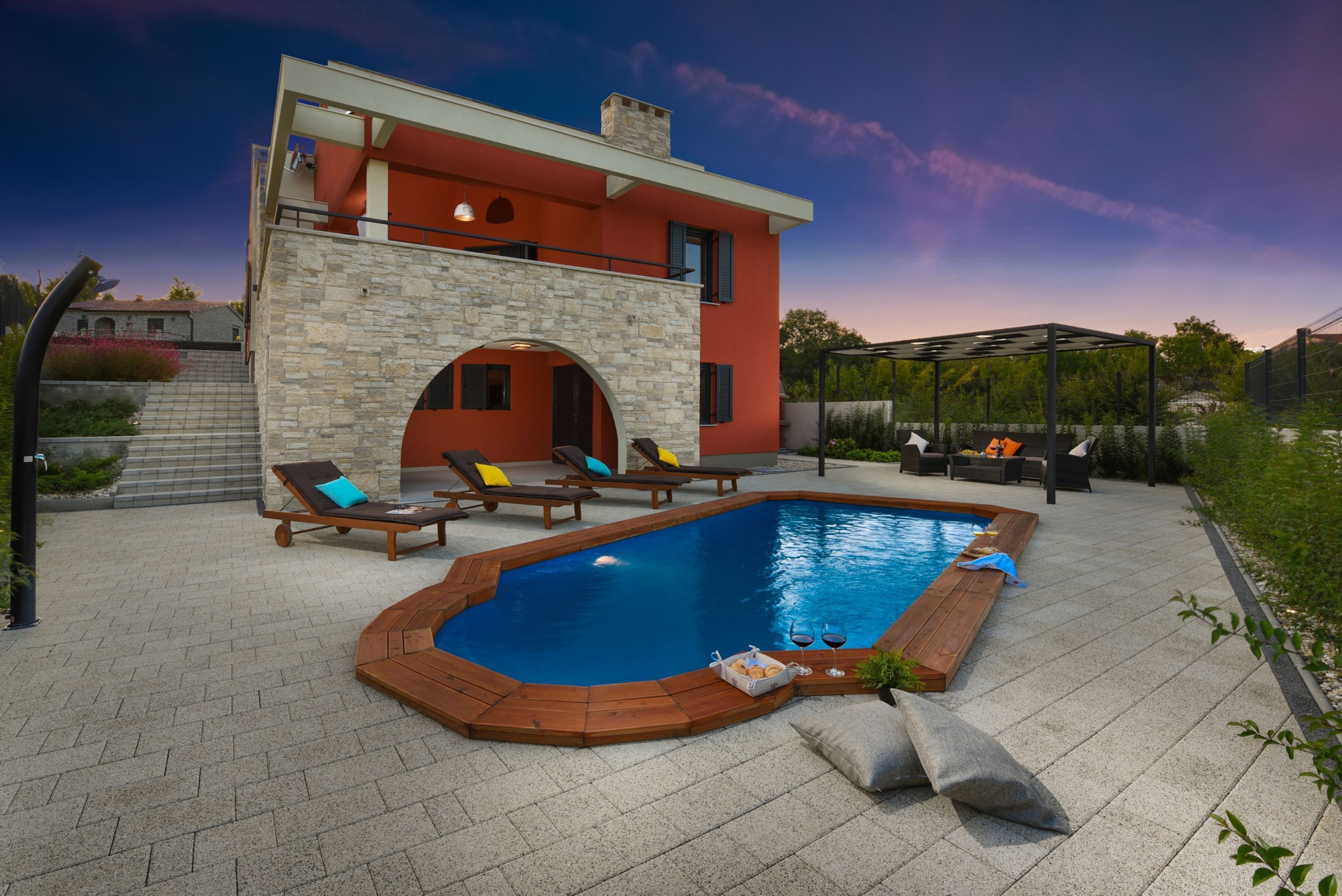 Une maison moderne dotée d’une piscine, de murs en pierre et d’un espace salon extérieur.