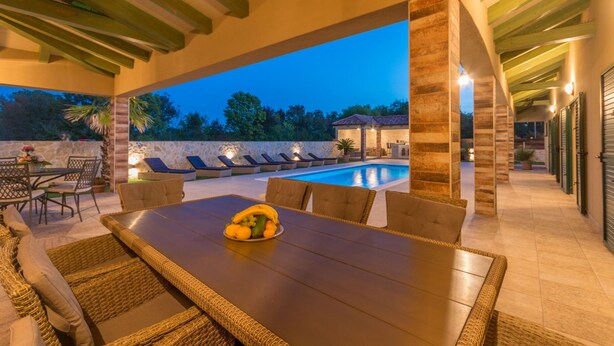 An outdoor dining area with a pool, stone walls, and a view of the surrounding landscape. - Villa Idassa Zadarvillas (Policnik)