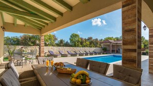 An outdoor dining area with a pool, wicker furniture, and a stone wall. - Villa Idassa Zadarvillas (Policnik)