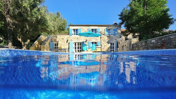 Ein Gebäude aus Stein mit einem Pool davor.