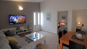 A modern living room with a flat-screen TV, a sofa, a coffee table, and a dining area with a table and chairs. - Villa Maraschino Zadarvillas (Vir)