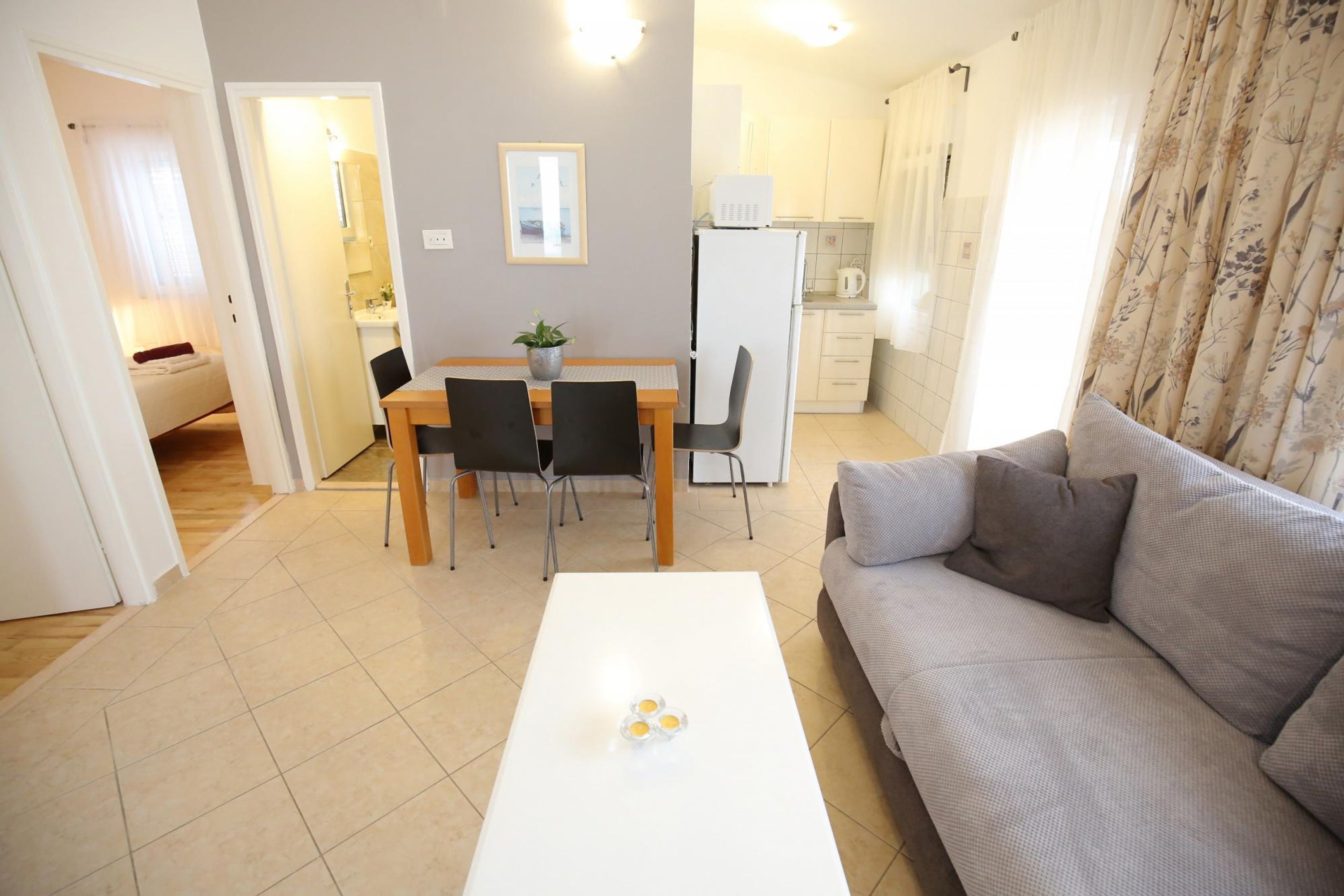 Un salon moderne avec un canapé gris, une table basse blanche et un coin repas comprenant une table et des chaises.