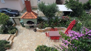A patio with stone flooring, outdoor seating, a brick oven, and surrounding greenery. - Villa Maraschino Zadarvillas (Vir)