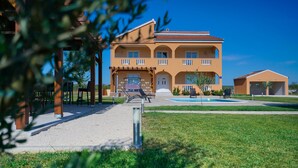 Un bâtiment à deux étages, doté d’un toit en tuiles, d’un patio couvert et d’une piscine.