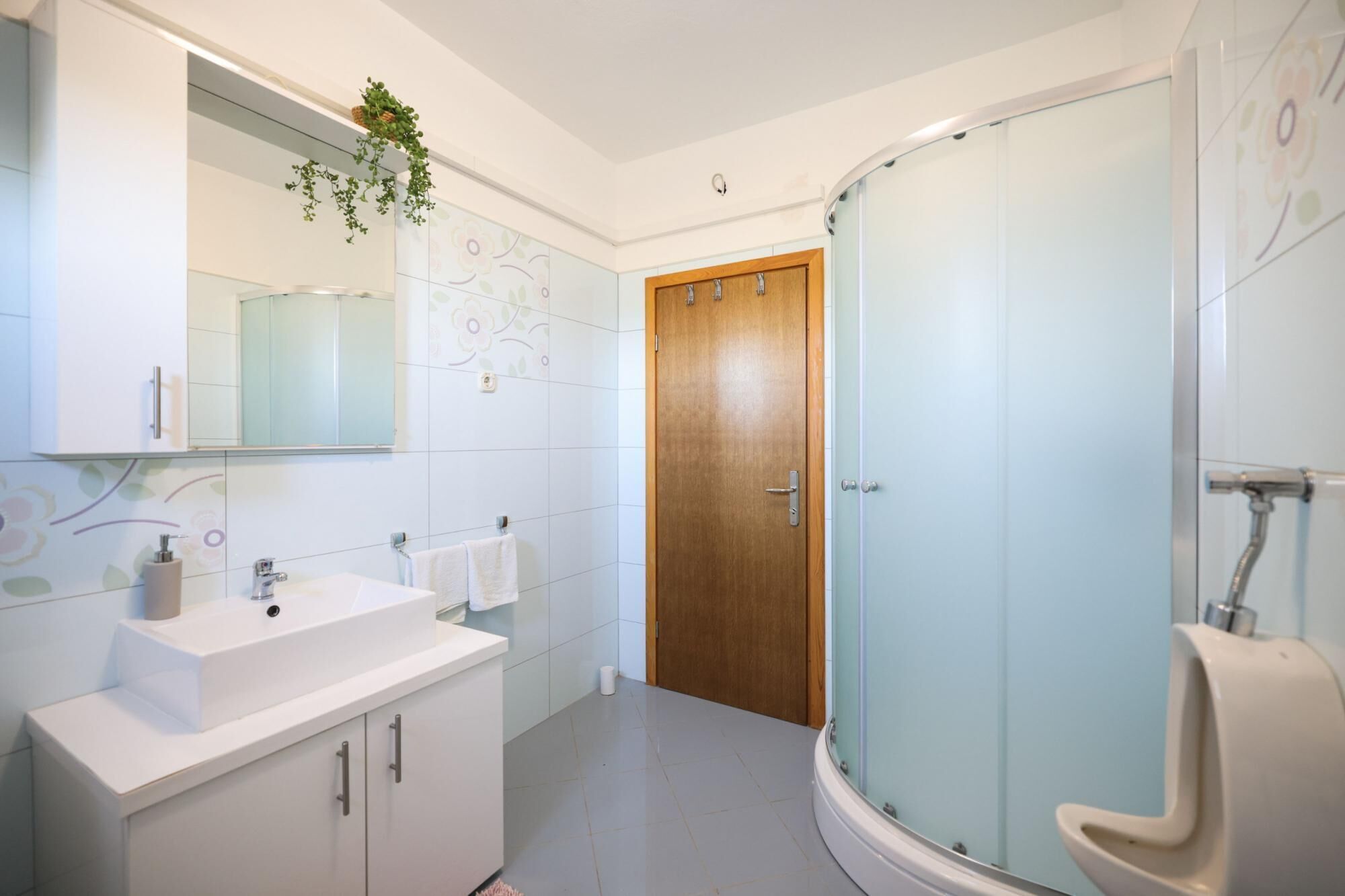 A modern bathroom with a sink, mirror, and shower.
