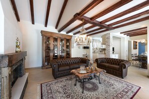 Un salon spacieux doté d’une cheminée, de deux canapés en cuir marron, d’une table basse en bois et d’un tapis à motifs.