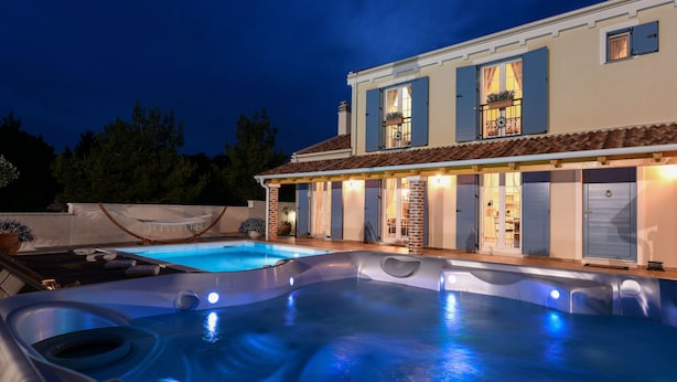 Ein Poolbereich mit Whirlpool und einem Haus im Hintergrund.