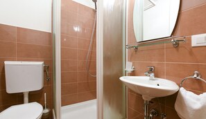 Bathroom features a shower enclosure, toilet, and sink with a towel rack.