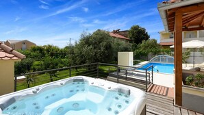 Ein Whirlpool auf einer Holterrasse mit einem Pool im Hintergrund.