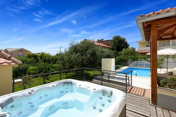 Relax in the hot tub or swim in the adjacent pool, surrounded by a lush lawn and trees.