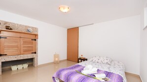 Ein Schlafzimmer mit einem Bett, einem Holzschrank, einem kleinen Tisch mit Orangensaft und einem dekorativen Gegenstand an der Wand.