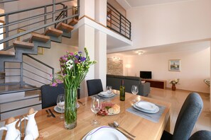 Enjoy meals in this stylish dining area with a wooden table for two, a vase with flowers, and a flat-screen TV.