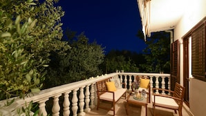 A balcony with a white balustrade, wooden furniture, and potted plants. - Villa Pine Zadarvillas (Kukljica)
