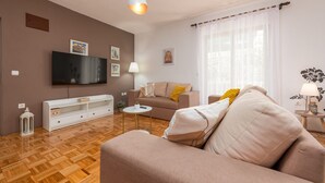 A modern living room with a flat-screen TV, a sofa, a coffee table, and a lamp. - Villa Pine Zadarvillas (Kukljica)
