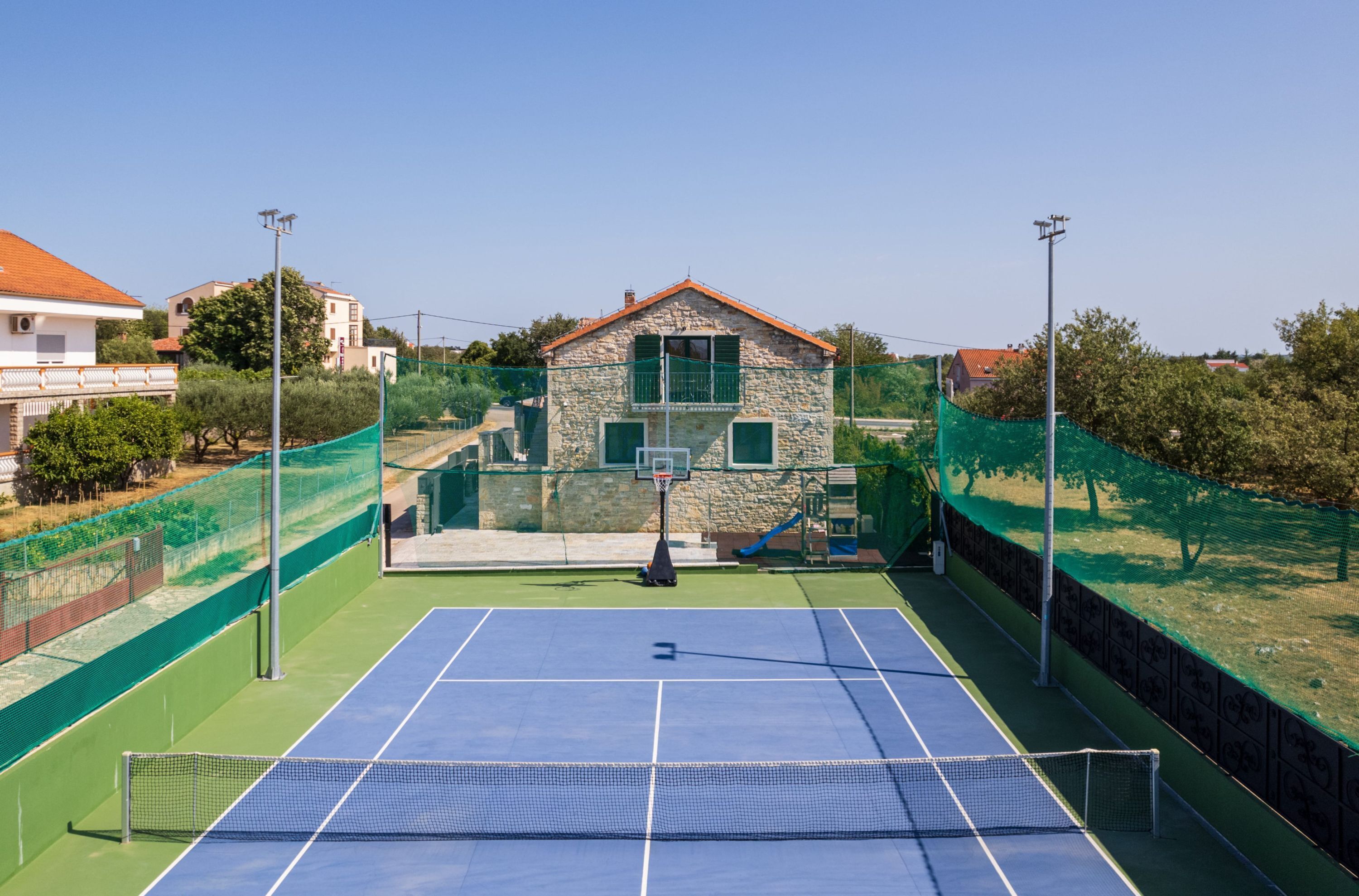An outdoor tennis court with a stone building in the background.