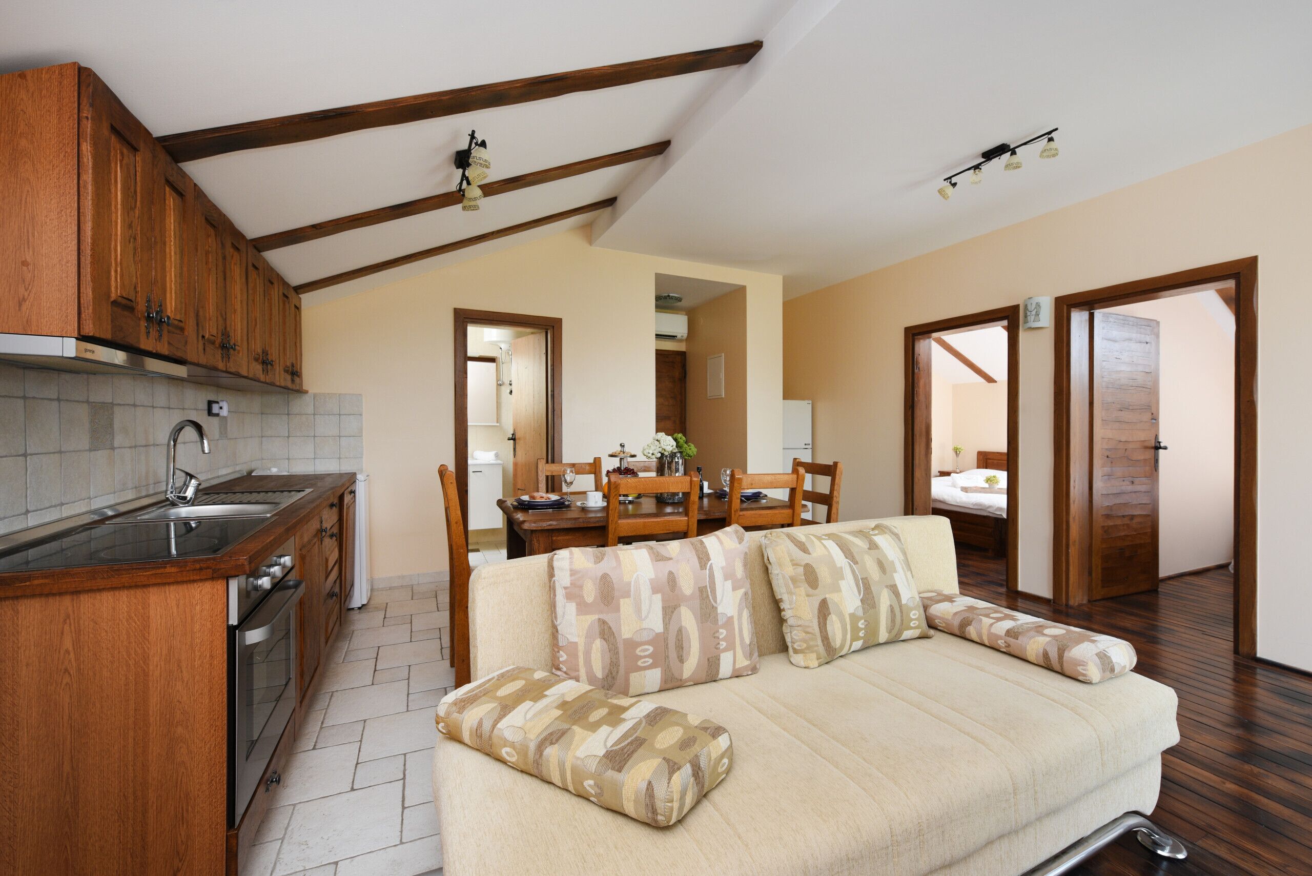 A cozy living room with a sofa, a wooden dining table, and a kitchen area with a sink and cabinets.