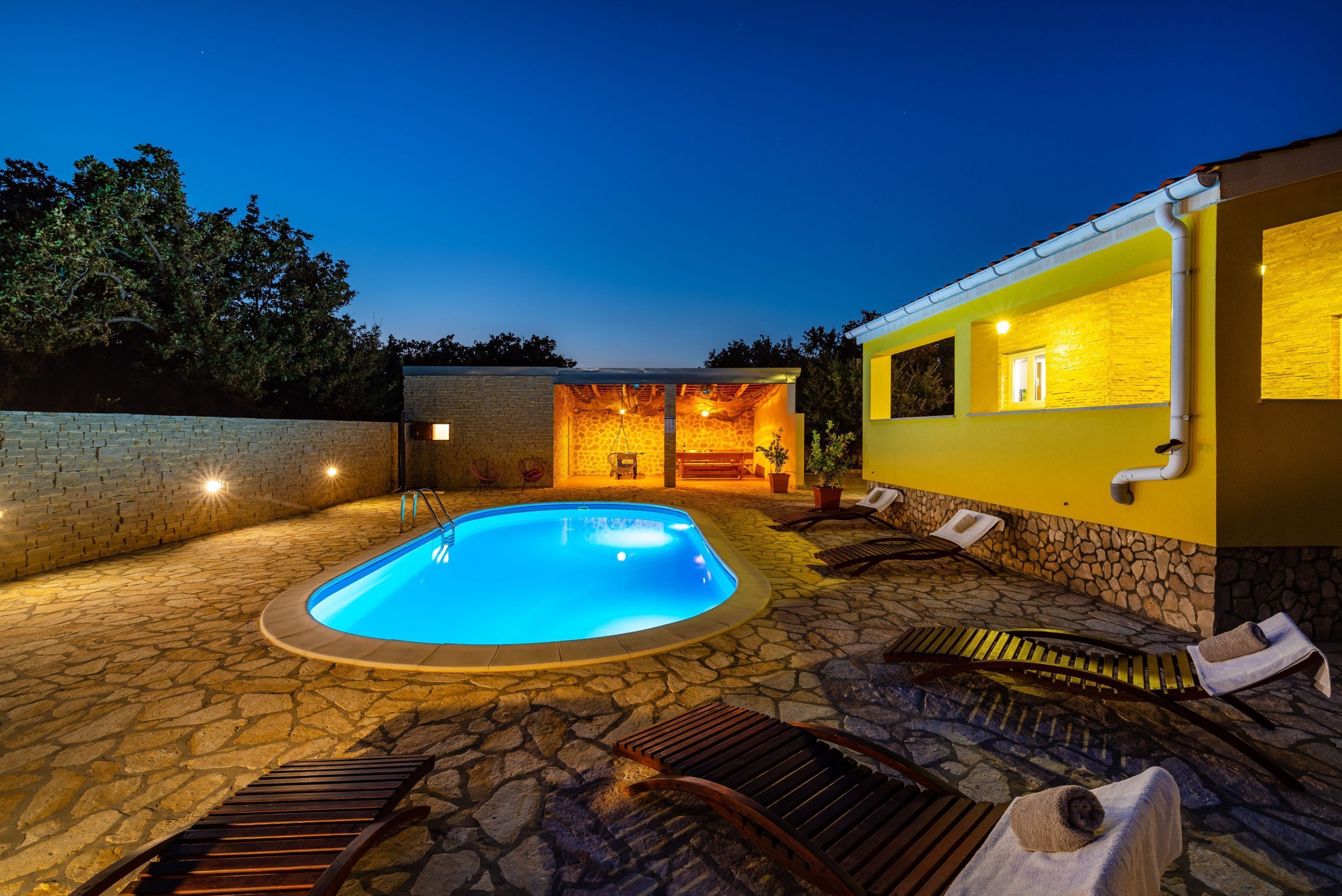 Una piscina con sillas de descanso y un patio de piedra.