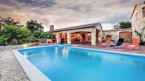 A swimming pool with a stone wall and lounge chairs. - Villa Smilje Zadarvillas (Posedarje)