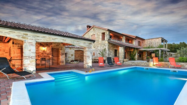 A poolside area with stone buildings, outdoor seating, and a clear sky. - Villa Smilje Zadarvillas (Posedarje)