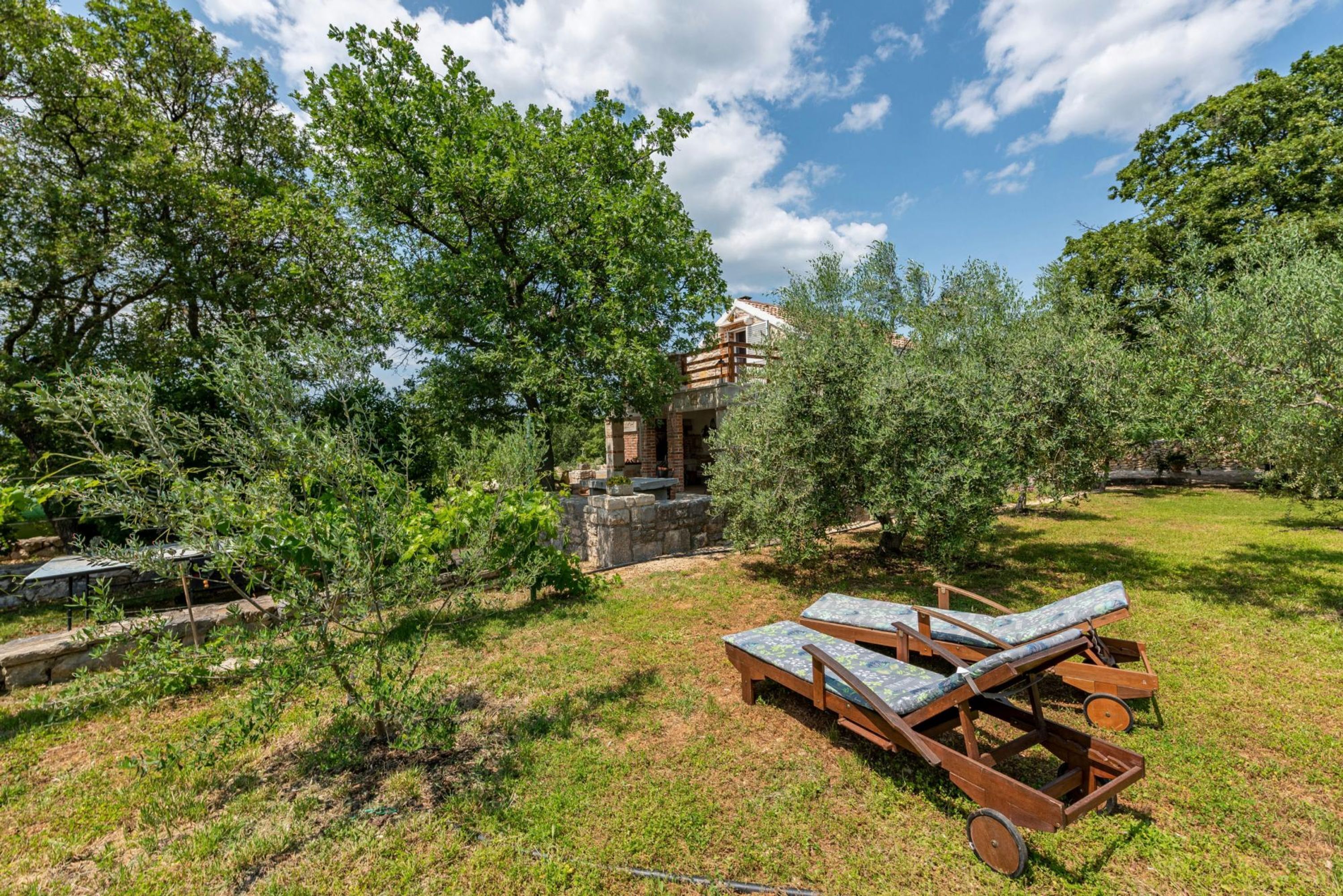 Un cadre extérieur rustique agrémenté d’une structure en pierre, de fauteuils et d’une végétation luxuriante.