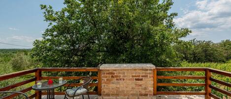 An outdoor patio with a brick wall, a wooden railing, and a table with chairs.