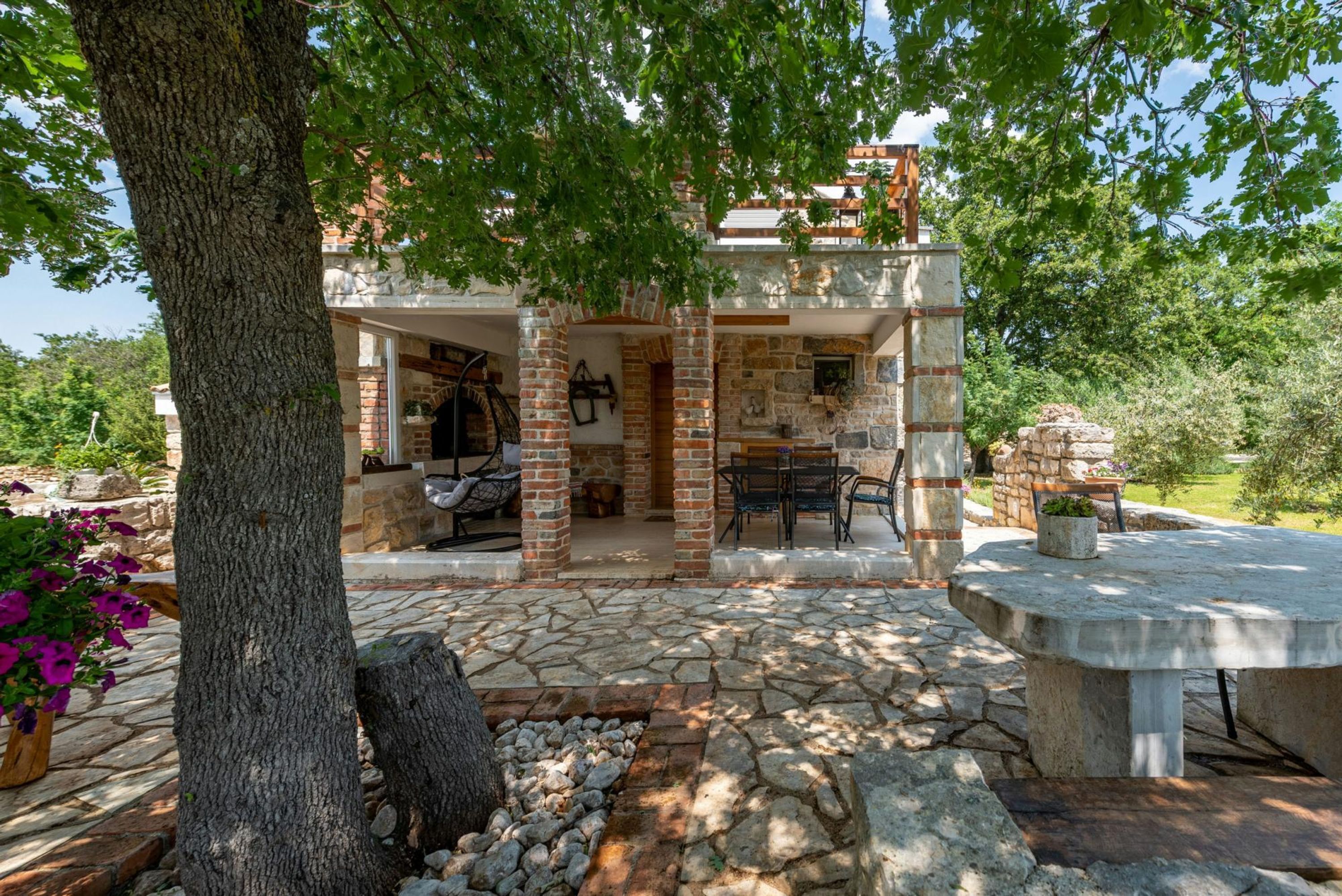 A stone building with a patio area, outdoor seating, and a stone fireplace.