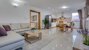 A modern living room with a sofa, coffee table, and a dining area with chairs and a table. - Villa Zlatni Dvori Zadarvillas (Razanac)