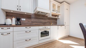Une cuisine moderne avec des meubles blancs, un four encastré et un plan de travail en bois.