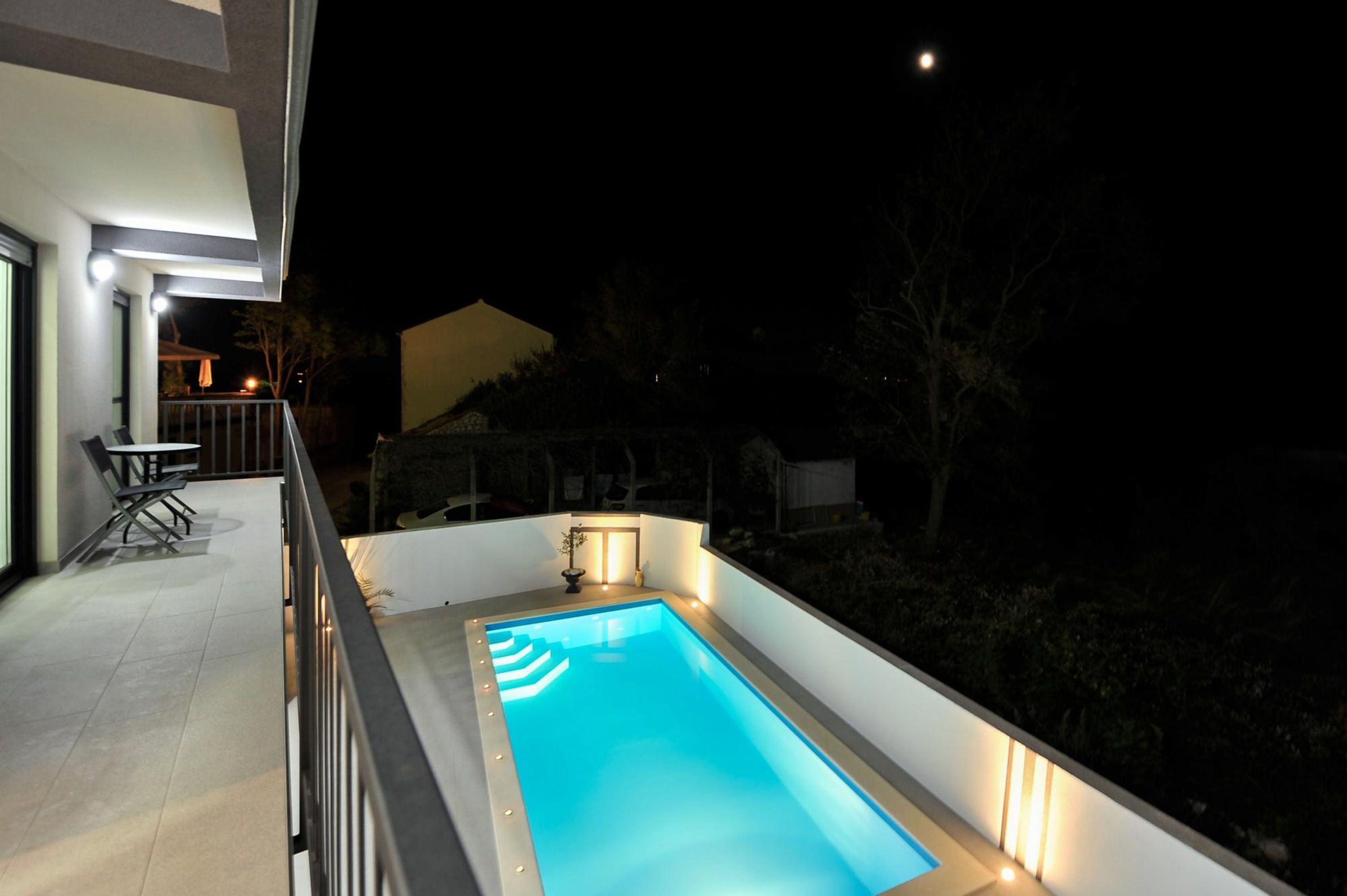 A rectangular swimming pool with a light blue interior, surrounded by a white deck and railing.