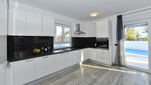 A modern kitchen with white cabinets, black countertops, and a large window. - Villa Lily Zadarvillas (Privlaka)