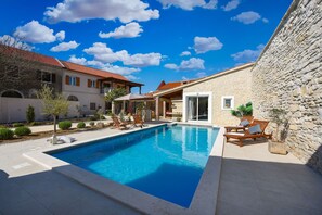 A swimming pool with lounge chairs and a stone wall. - Villa Granar Zadarvillas (Benkovac)