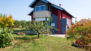 Une maison moderne à deux étages, dotée d’une façade en pierre et d’un toit bleu.