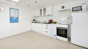 Eine moderne Küche mit weißen Schränken, einem Geschirrspüler, einem Backofen und einer Mikrowelle.
