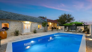 A stone house with a swimming pool, outdoor seating, and a well-lit entrance. - Villa Outback Zadarvillas (Benkovac)