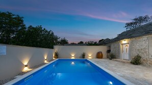 A swimming pool with stone walls and a stone building with a door. - Villa Outback Zadarvillas (Benkovac)