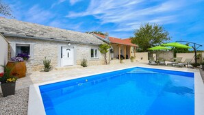A stone building with a swimming pool, outdoor seating, and a clear blue sky. - Villa Outback Zadarvillas (Benkovac)