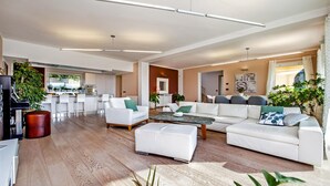 Un amplio salón con un sofá blanco, una mesa de centro y una zona de comedor al fondo.