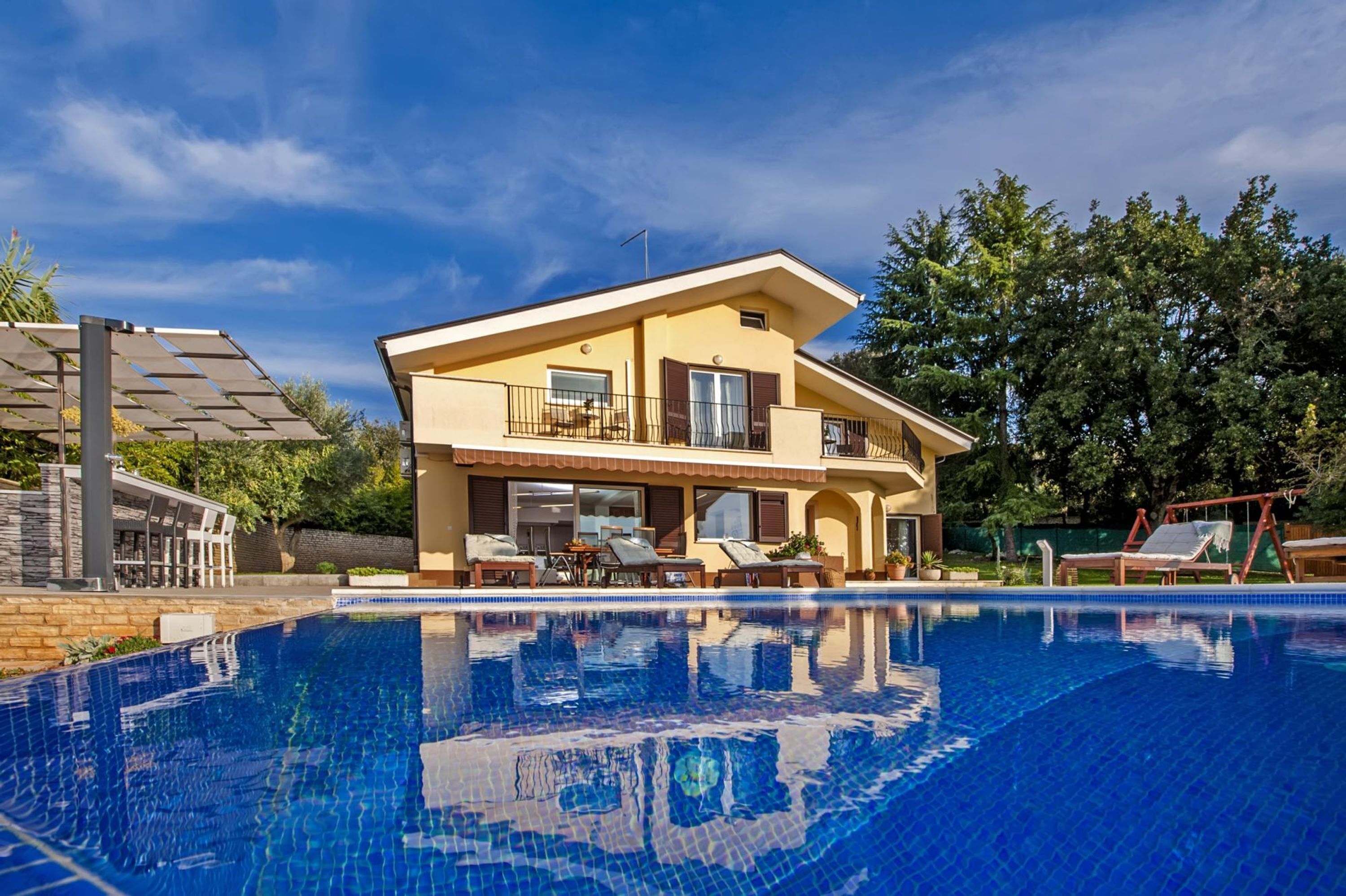 Ein zweistöckiges Haus mit Schwimmbecken davor.