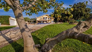 Una casa de dos pisos con un jardín delantero, un garaje y un árbol en primer plano.