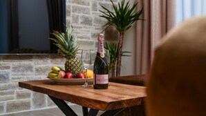 Une table en bois avec une bouteille de champagne, un verre et un saladier de fruits.