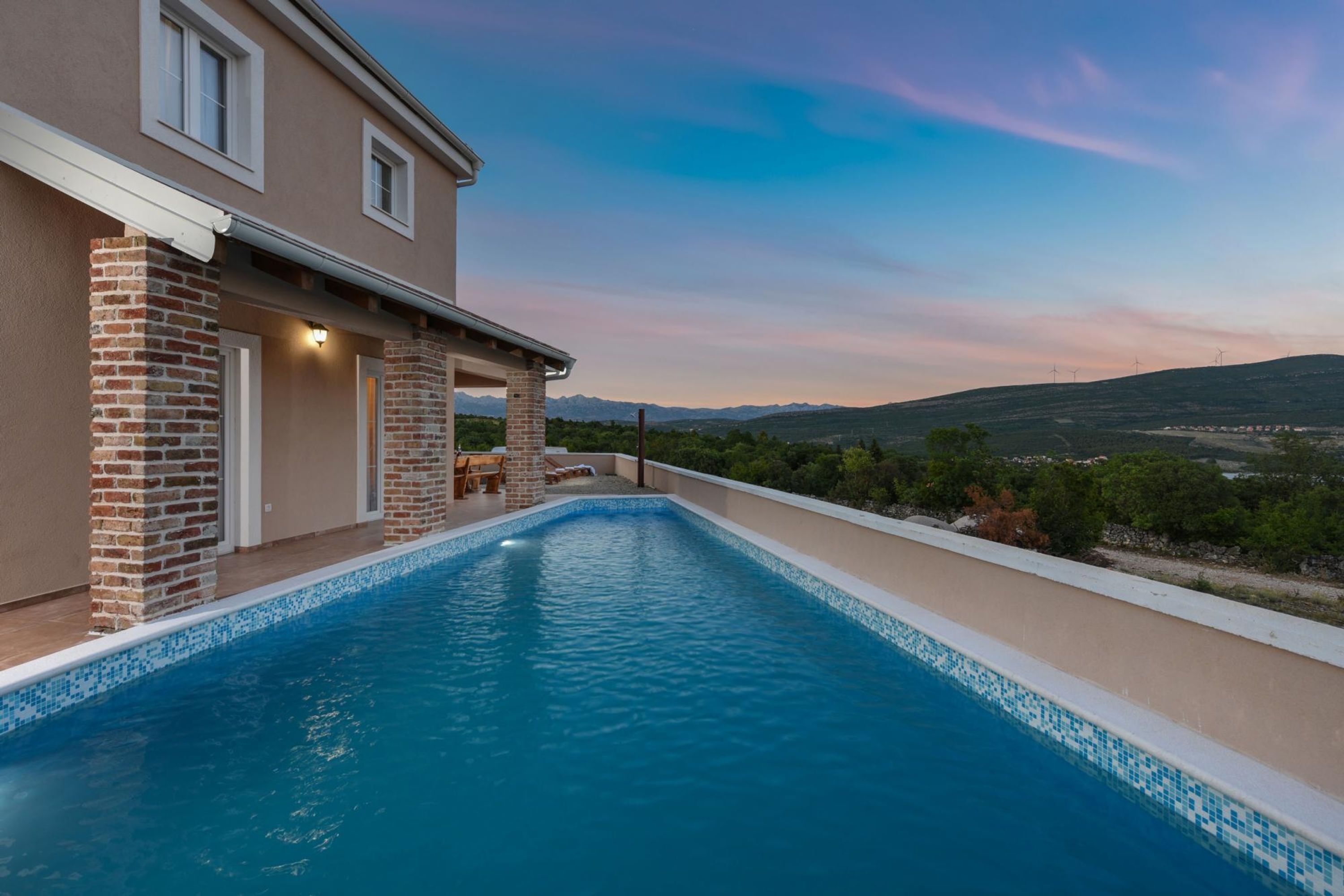 A swimming pool with a view of a house and distant mountains.