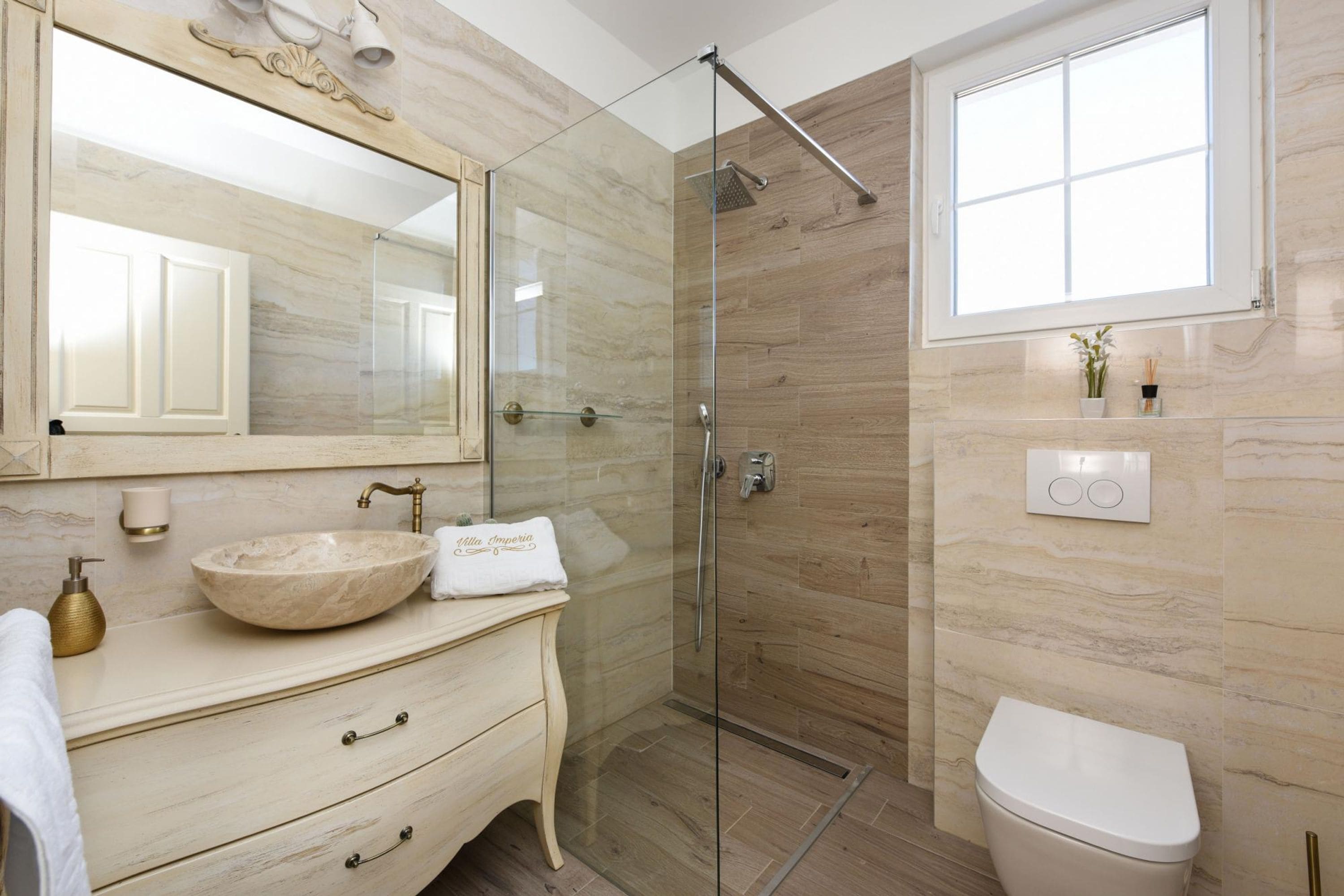 Une salle de bain moderne avec un meuble-lavabo en marbre, une cabine de douche en verre et des toilettes.