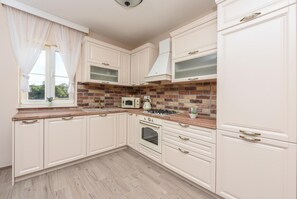 Kitchen features a microwave, stove, and oven, with a window offering natural light.