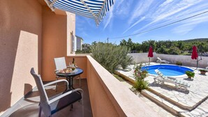 A balcony with a table and chairs, a pool, and red umbrellas. - Villa Nea Zadarvillas (Posedarje)